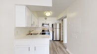 This thoughtfully designed 1-bedroom, 1-bathroom residence at 2801 Park Center Drive offers a clean, modern aesthetic throughout its efficiently laid-out floor plan. The open living area is bathed in natural light, thanks to large sliding glass doors that lead to a private balcony overlooking mature trees and greenery. Light-toned luxury vinyl plank flooring runs through the main living spaces, complementing the bright white walls and textured ceilings that are consistent throughout. A ceiling fan adds comfort to the living area, which also benefits from an additional window fitted with blinds for adjustable light control. The kitchen is well-equipped with stainless steel appliances, including a refrigerator, electric range, over-the-range microwave, and dishwasher. Crisp white shaker-style cabinetry extends to the ceiling, offering generous storage, while the light countertops provide ample workspace. The bedroom features plush wall-to-wall carpeting, a large window for natural light, and direct access to a closet and bathroom hallway. The bathroom area includes a linen closet with built-in shelving for additional storage. A dedicated entrance and separate closet round out this functional and well-organized residence.