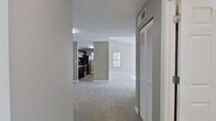 This contemporary apartment offers a thoughtfully designed living space. The open floor plan creates a seamless flow between the living area and kitchen, enhanced by large windows that flood the rooms with natural light. The kitchen boasts dark wood cabinetry, stainless steel appliances, and sleek countertops. Plush carpeting in the main living areas contrasts with durable wood-look flooring in the kitchen and bathroom. The bathroom features a modern vanity and fixtures. Ceiling fans and in-unit laundry add convenience, while the neutral color palette throughout provides a versatile backdrop for various decor styles.
