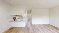 Located at 5300 Newcastle Ave in the Encino neighborhood of Los Angeles, this one-bedroom, one-bathroom unit offers a clean and functional single-floor layout. Light wood-tone flooring runs throughout the living areas and bedroom, creating a cohesive and bright interior. The open living room and kitchen area is anchored by a wall-mounted air conditioning unit and large windows dressed with vertical blinds, allowing ample natural light to fill the space. The kitchen is efficiently arranged with white cabinetry, a gas range with overhead ventilation, a refrigerator, a double basin sink, and light stone-finish countertops — all finished in a crisp, all-white palette with tile flooring. The spacious bedroom features the same warm wood flooring and a window with vertical blinds that brings in natural light. A notable feature is the dedicated walk-in closet, equipped with double hanging rods and built-in shelving on two walls, offering generous storage capacity. The bathroom is clean and simply appointed with a full tub-shower combination, white tile surround, chrome fixtures, and a window for natural ventilation. The overall ambiance of the unit is bright, neutral, and move-in ready.