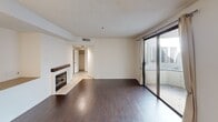 This single-floor residence offers a thoughtfully designed layout across several well-appointed rooms. The living area serves as the heart of the home, showcasing rich, dark hardwood flooring that extends throughout the main spaces. A white-framed fireplace with a dark wood mantle adds a classic focal point to the room, while a curved half-wall partition subtly defines the transition between the living and dining areas. A chandelier overhead adds a touch of elegance, and a textured ceiling lends architectural character. Large sliding glass doors invite natural light into the living space and provide direct access to an outdoor area, creating a seamless indoor-outdoor connection. The kitchen is equipped with dark espresso-toned cabinetry, both upper and lower, complemented by light countertops and a stainless steel double-basin sink with a modern pull-down faucet. The bathrooms include a full tub-and-shower combination — one featuring clean white surrounds, and another showcasing elegant floor-to-ceiling marble-style tile with a built-in tub and an opaque window for natural light and privacy. Together, these spaces create a cohesive and functional living environment with a balanced mix of classic and contemporary design elements.