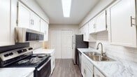 This single-floor residence offers a well-organized layout designed for comfortable everyday living. The galley-style kitchen is a functional highlight, featuring white cabinetry with brushed nickel hardware, marble-style countertops, a subway tile backsplash, stainless steel sink with a gold-tone faucet, and black and stainless appliances including a range, microwave, dishwasher, and refrigerator. A skylight-style overhead fixture brightens the space, and wood-look flooring runs throughout the kitchen.

The living area is spacious and carpeted, anchored by a fireplace and a sliding glass door that opens to a private balcony with outdoor views. Natural light filters in through the vertical blinds, creating an open and airy atmosphere.

A long carpeted hallway connects the bedrooms, each of which is comfortably sized with plush carpet, ceiling fans with light fixtures, and windows that bring in natural light. The layout also includes a partially open entryway area that adds a sense of depth to the floor plan.

The bathrooms are finished with marble-style vanity countertops, wood-look flooring, brushed nickel fixtures, and tub-shower combinations with white tile surrounds. Neutral tones throughout the unit create a clean, cohesive aesthetic.