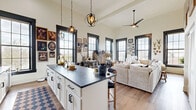 Located at 106 Main St in Hamilton, Ohio, this one-bedroom, one-bathroom residence offers a thoughtfully designed single-floor layout with an open, airy feel. Soaring ceilings and large, black-framed multi-pane windows define the living and kitchen area, flooding the space with natural light and offering views of the surrounding streetscape. Exposed brick along one wall adds an industrial warmth that complements the otherwise clean, modern aesthetic.

The kitchen is well-appointed with white shaker cabinetry, dark granite countertops, stainless steel appliances, and a central island with seating — pendant globe lighting above adds a refined touch. The open-concept layout flows seamlessly into the living area, creating a cohesive and functional shared space with durable wood-style flooring throughout.

The spacious primary bedroom accommodates large furniture comfortably and features a tall black-framed window that brings in natural light. The bathroom includes a granite-topped vanity with white cabinetry, a shower/tub combo, wood-style flooring, and a striking dark-paneled door that adds a modern contrast to the bright, neutral walls. The overall ambiance of the unit is warm, urban, and full of character.