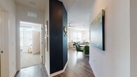 This single-floor residence combines contemporary design with vibrant, curated interiors throughout. The entryway sets the tone immediately, featuring a striking navy accent wall paired with rich hardwood-style flooring that extends throughout the main living areas. A large-scale abstract canvas greets guests along the hallway, leading seamlessly into the combined dining and living space.

The living room is bright and inviting, with generous windows dressed in sheer white curtains and plantation shutters that allow abundant natural light. A ceiling fan anchors the room, which flows naturally into the dining area furnished with emerald green chairs around a round table. The kitchen offers ample cabinetry in a warm greige finish, granite countertops, a classic white subway tile backsplash, and a full suite of stainless steel appliances.

Both bedrooms feature distinct accent walls — one in soft sky blue and one in deep navy — lending each room a defined character. The bathrooms maintain the same refined finishes seen throughout, with granite-topped vanities, dark cabinetry, and hardwood-style flooring. The overall ambiance of the residence is cohesive and polished, balancing bold color choices with clean architectural lines for an inviting, well-designed living environment.
