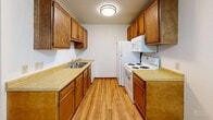 This 2-bedroom, 1-bathroom unit in Sioux Falls, South Dakota offers a practical and well-organized single-floor layout. The galley-style kitchen is equipped with warm oak cabinetry, ample upper and lower storage, light countertops, a double sink, and white appliances including a range, microwave, and refrigerator, all set on easy-care hardwood-style flooring. The adjacent living room is generously sized, featuring plush carpeting, a sliding glass door that opens to a private balcony overlooking lush greenery, and a wall-mounted air conditioning unit for added comfort. Baseboard heating runs throughout the unit, ensuring consistent warmth. The primary bedroom offers comfortable proportions with carpet flooring, a ceiling fan with light fixture, a wood-framed window that brings in natural light, and a sliding closet. The second bedroom is equally well-appointed, featuring carpet, a bright window with outdoor views, and a large sliding closet. The full bathroom includes a tub-shower combination, a vanity with oak cabinetry, overhead storage, and tile flooring. Textured ceilings are consistent throughout the unit, adding a classic residential character to the overall space.
