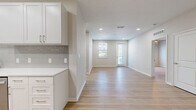 Located at 605 4th Ave NW in Largo, FL, this thoughtfully designed 2-bedroom, 2-bathroom single-story home offers a bright, modern living experience. Light wood-tone flooring flows seamlessly throughout, tying together a clean, cohesive aesthetic accented by crisp white walls and recessed lighting.

The open-concept kitchen and living area forms the heart of the home. The kitchen is well-appointed with white shaker cabinetry, quartz countertops, a subway tile backsplash, and a full suite of stainless steel appliances including a refrigerator, range, microwave, and dishwasher. The adjacent living area extends toward a front entry with large windows and a glass-paneled door that invites natural light throughout the space.

The spacious primary bedroom includes a walk-in closet outfitted with wire shelving for ample storage. Both bathrooms are finished to a high standard; the primary bath features a double-sink vanity with white cabinetry, brushed nickel hardware, framed mirrors, and a glass-enclosed shower. The second bedroom features a ceiling fan and a window with outdoor views.

A dedicated laundry area with a full-size washer and dryer adds everyday convenience. The home's neutral palette and modern finishes create a clean, move-in-ready environment throughout.