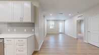 Located at 605 4th Ave NW in Largo, FL, this thoughtfully designed 2-bedroom, 2-bathroom single-story home offers a bright, modern living experience. Light wood-tone flooring flows seamlessly throughout, tying together a clean, cohesive aesthetic accented by crisp white walls and recessed lighting.

The open-concept kitchen and living area forms the heart of the home. The kitchen is well-appointed with white shaker cabinetry, quartz countertops, a subway tile backsplash, and a full suite of stainless steel appliances including a refrigerator, range, microwave, and dishwasher. The adjacent living area extends toward a front entry with large windows and a glass-paneled door that invites natural light throughout the space.

The spacious primary bedroom includes a walk-in closet outfitted with wire shelving for ample storage. Both bathrooms are finished to a high standard; the primary bath features a double-sink vanity with white cabinetry, brushed nickel hardware, framed mirrors, and a glass-enclosed shower. The second bedroom features a ceiling fan and a window with outdoor views.

A dedicated laundry area with a full-size washer and dryer adds everyday convenience. The home's neutral palette and modern finishes create a clean, move-in-ready environment throughout.