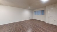 Located at 20551 Osage Ave in Torrance, California, this single-floor unit offers a straightforward and functional layout suited for comfortable everyday living. The main living area is generously sized, featuring dark hardwood-style flooring, crisp white walls, and a textured ceiling with a ceiling fan providing both lighting and air circulation. A wall-mounted AC unit serves the space, and recessed lighting adds a clean, modern touch. The open layout connects seamlessly to the kitchen area via a partial partition wall, enhancing the sense of flow throughout.

The kitchen is efficiently designed with white cabinetry, gray speckled countertops, a double basin sink, and white appliances including an electric range and an over-the-range microwave. The hardwood-style flooring continues into this space, maintaining visual consistency.

A separate room features plush carpeting and textured ceilings, offering a quieter, more private setting. It is served by a wall-mounted AC unit and benefits from a window with vertical blinds allowing natural light.

The bathroom includes an extended vanity with gray countertops, white cabinetry offering ample storage, a large mirror, and a separate toilet area. The hardwood-style flooring carries through here as well, completing the cohesive aesthetic of the unit.