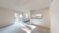 This thoughtfully laid-out single-floor residence offers a comfortable and functional living experience across a well-proportioned floor plan. The combined kitchen and living room serves as the heart of the home, featuring plush wall-to-wall carpeting in the living area and smooth wood-look flooring in the kitchen. Natural light floods the space through a large sliding glass door that opens onto a private balcony, offering outdoor views and an inviting indoor-outdoor connection. An additional window further brightens the living area, enhancing the open and airy feel.

The kitchen is designed for practicality, featuring white cabinetry with ample storage, dark granite-style countertops, and white appliances including a range, microwave, refrigerator, and dishwasher. A pass-through window connects the kitchen to the living area, creating an open and social atmosphere.

The bedroom is a quiet, carpeted retreat with a window dressed with vertical blinds, providing natural light and privacy. A dedicated closet with built-in shelving and hanging rods offers generous storage. The full bathroom is clean and classic, featuring a tiled shower-tub combo with chrome fixtures. A hallway connects the rooms, completing this efficient and comfortable layout.
