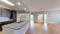 Located at 5672 Infinity Ln in Virginia Beach, VA, this single-floor unit offers three bedrooms and three bathrooms within a well-designed, open-concept layout. The combined kitchen and living area forms the heart of the home, where warm wood-style flooring, recessed lighting, and a ceiling fan create a bright and functional atmosphere. A door in the living room provides natural light and outdoor access, while additional windows keep the space airy.

The kitchen is well-appointed with dark espresso cabinetry, stainless steel appliances including a refrigerator, range, and microwave, granite countertops, a mosaic tile backsplash, and a peninsula with a built-in sink — ideal for both cooking and casual dining.

The primary bedroom features plush carpeting and double doors leading to a private en-suite bathroom, which includes a dual-sink granite vanity, tile flooring, a soaking tub, and direct access to a walk-in closet with built-in shelving. The additional bedrooms are carpeted with natural light from windows. A dedicated laundry area houses a full-size washer and dryer. Two closets and a hallway complete the thoughtfully organized floor plan.