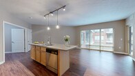 Located at 205 Vine St in Columbus, Ohio, this well-appointed 2-bedroom, 2-bathroom residence offers a thoughtfully designed single-floor layout. Rich hardwood-style flooring flows throughout the main living areas, creating a warm and cohesive aesthetic.

The open-concept kitchen and living room serve as the heart of the home. The kitchen features a central island with pendant lighting overhead, light maple cabinetry, stainless steel appliances including a dishwasher, microwave, and refrigerator, and a tile backsplash. Large sliding glass doors and wide windows flood the living area with natural light and provide direct access to a private balcony with exterior views.

The primary bedroom is a generously sized retreat with a spacious walk-in closet fitted with wire shelving for ample storage. Its en-suite bathroom boasts a dual-sink vanity with light wood cabinetry, a large mirror, and a glass-enclosed walk-in shower with hardwood-style flooring. The second bedroom includes its own closet with sliding doors. The second bathroom features a full soaking tub and shower combo, single vanity, and matching hardwood-style flooring. A hallway and two closets round out the practical and functional layout of this residence.