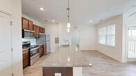 Located at 288 E Ridgeway Rd in Commerce, GA, this single-floor, one-bedroom, one-bathroom residence offers a thoughtfully designed open-concept layout with modern finishes. Light-toned luxury vinyl plank flooring runs throughout the space, lending a clean and cohesive aesthetic.

The kitchen serves as the centerpiece of the living area, anchored by a large granite-topped island with an integrated sink and pendant lighting overhead. Rich, warm-toned cabinetry pairs with stainless steel appliances — including a range, microwave, and refrigerator — to create a functional and visually appealing cooking space. Recessed lighting illuminates the open living area beyond the island.

The bedroom offers a comfortable, serene retreat with multiple windows dressed in white horizontal blinds, allowing abundant natural light and outdoor views of surrounding greenery. A ceiling fan adds comfort, and a dedicated closet provides practical storage.

The bathroom maintains the same design language as the rest of the unit, with a granite-topped vanity, warm wood cabinetry, a large mirror, and an elegant multi-bulb light fixture above. Light flooring and neutral white walls create a bright, clean atmosphere.

Overall, the space presents a cohesive, modern interior with consistent finishes, ample natural light, and a practical, well-organized floor plan.