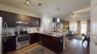 This well-appointed single-story residence showcases a thoughtfully designed open-concept layout that seamlessly connects the kitchen, dining, and living areas. The kitchen is a standout feature, boasting rich dark cabinetry paired with granite countertops, a classic subway tile backsplash, and a full suite of stainless steel appliances including a range, microwave, dishwasher, and refrigerator. A peninsula with an undermount double sink and pendant lighting overhead adds both functionality and style. Track lighting throughout enhances the modern aesthetic.

The living area features warm wood-style flooring and is anchored by a bold accent wall, with large windows and sliding glass door access that invite natural light and outdoor views. The adjacent dining space comfortably accommodates a full dining set. Bedrooms are carpeted for comfort, each featuring accent walls, ample natural light from large windows, and direct access to well-appointed bathrooms. Each bathroom includes granite-topped vanities, dark cabinetry, wood-style flooring, and a tub-shower combination. The overall ambiance is contemporary and cohesive, with neutral tones and refined finishes throughout.