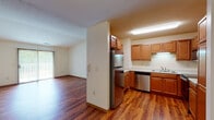 This single-floor residence offers a well-organized layout with a cohesive design throughout. Warm hardwood-style flooring extends across the main living areas, complemented by neutral-toned walls and classic wood-trimmed doors and baseboards that provide a consistent aesthetic.

The kitchen is thoughtfully equipped with stainless steel appliances, including a refrigerator, electric range, microwave, and dishwasher. Warm-toned wood cabinetry provides generous storage, while light countertops offer ample workspace. The kitchen opens toward the living area, creating a connected, functional flow. A sliding glass door in the living space introduces natural light and outdoor access.

The bedrooms feature plush carpeting and ceiling fans, with windows that bring in natural greenery views. One bedroom benefits from vaulted ceilings, adding a sense of openness, and includes access to a walk-in closet. The entry and common areas are finished with the same rich hardwood-style flooring and a pendant light fixture.

Two bathrooms serve the residence: one features a walk-in shower with sliding glass doors and wood-toned cabinetry, while the second offers a full soaking tub and tiled flooring, providing practical versatility for residents.