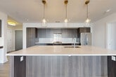 Located in Arlington, VA, this contemporary 4-bedroom, 2-bathroom residence offers a thoughtfully designed single-floor layout with modern finishes throughout. Wide-plank hardwood flooring flows seamlessly across every room, anchoring the home's clean, cohesive aesthetic.

The open-concept kitchen is a standout feature, showcasing a generous island with a quartz countertop, dark wood-grain cabinetry extending floor to ceiling, a glass tile backsplash, stainless steel appliances, and three elegant pendant lights overhead. This kitchen opens directly into the combined dining and living area, which is bathed in natural light through expansive floor-to-ceiling sliding glass doors leading to a private balcony with views of the surrounding Arlington streetscape.

The four bedrooms are well-proportioned, each featuring large windows that allow abundant natural light. The spacious primary bedroom provides ample room for furnishings. Six closets throughout the unit ensure generous storage, including dedicated walk-in closet space. The two bathrooms are finished with large-format light tile flooring, white subway tile surrounds, soaking tubs, and warm wood vanities. A dedicated laundry room adds everyday convenience. The overall ambiance is bright, clean, and contemporary.
