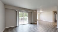 This single-floor residence offers a thoughtfully designed layout with modern updates and a clean, neutral palette throughout. The open living area is a standout feature, anchored by durable wood-look flooring and a large sliding glass door that floods the space with natural light and provides direct access to a private deck overlooking lush greenery. An accent wall with painted white brick adds texture and character to the living space.

The kitchen has been tastefully updated with two-tone cabinetry — white upper cabinets paired with dark lower cabinets — complemented by marble-style countertops, a white subway tile backsplash, stainless steel appliances, and a wall-mounted range hood. A dedicated dining area adjacent to the kitchen offers a natural flow for everyday living.

The bedrooms feature soft carpeting, generous closet space with built-in rods, and windows that bring in abundant natural light with views of surrounding trees. The bathroom is finished with light wood-look flooring, a tiled tub-and-shower combination featuring a decorative blue mosaic accent strip, and clean white fixtures.

Throughout the residence, consistent wood-look flooring, neutral gray walls, and bright white trim create a cohesive and modern atmosphere that is both functional and inviting.