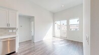 This thoughtfully designed 2-bedroom, 2-bathroom residence in San Diego, CA offers a bright and modern living experience on a single floor. The open-concept living, dining, and kitchen area serves as the heart of the home, bathed in natural light streaming through large sliding glass doors that lead to a private balcony with views of the surrounding neighborhood. Soaring ceilings amplify the sense of space throughout, while durable hardwood-style flooring flows seamlessly across the entire unit.

The kitchen is a standout feature, outfitted with crisp white shaker cabinetry, a neutral tile backsplash, light quartz-style countertops, a deep single-basin sink, and a full suite of stainless steel appliances including a range, microwave, and dishwasher. A hallway connects the living areas to both bedrooms, each offering tall ceilings, generous natural light, and dedicated closet space. The primary bedroom provides a comfortable, well-proportioned retreat.

Both bathrooms are finished in a clean, all-white palette featuring tiled tub-shower combinations with matte black fixtures, adding a modern contrast. Additional conveniences include in-unit laundry and two hallways that enhance traffic flow throughout the home. The overall aesthetic is clean, contemporary, and move-in ready.
