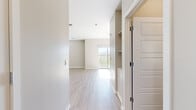 Located at 11330 W Van Buren St in Avondale, Arizona, this thoughtfully designed single-floor unit offers a clean, modern aesthetic with a cohesive neutral palette throughout. Light-toned luxury vinyl plank flooring runs seamlessly across the entire space, complementing the crisp white trim and soft greige walls.

The open-concept kitchen and living area serves as the heart of the unit. The kitchen is outfitted with grey shaker-style cabinetry, stainless steel appliances including a refrigerator, range, and microwave, a white subway tile backsplash, and a peninsula island with a white quartz countertop and undermount sink — ideal for both meal prep and casual dining. The living area benefits from a sliding glass door that invites abundant natural light and outdoor views, while a ceiling fan overhead adds comfort and airflow.

A hallway connects the main living space to the remaining rooms, including a well-proportioned bedroom featuring its own ceiling fan, a window with blinds for natural light and privacy, and access to a dedicated closet. The bathroom is finished to a high standard, showcasing grey shaker vanity cabinets, a white quartz countertop, an LED-backlit mirror, and a full tub-shower combination with floor-to-ceiling grey tile surround.