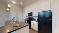 Located at 751 E Wheeling St in Lancaster, Ohio, this single-floor residence offers a thoughtfully designed layout with contemporary finishes throughout. The open-concept kitchen serves as the heart of the space, showcasing crisp white cabinetry extending to the ceiling, dark countertops, and a full suite of black appliances including a refrigerator, electric range, and over-the-range microwave. A central island with an integrated sink and pendant lighting overhead adds both functionality and visual appeal, making the kitchen ideal for cooking and casual dining. Wood-style plank flooring runs throughout the unit, lending warmth and continuity to the overall design. The bedrooms are generously sized with neutral-toned walls, ceiling fans, and ample natural light from window treatments. The bathrooms are finished consistently with the kitchen, featuring white vanity cabinetry, dark countertops, large mirrors, and wood-style flooring. One bathroom includes a shower-tub combination, while another is appointed with grab bars for added accessibility. Recessed and pendant lighting complement the airy feel of the space. The clean, neutral palette and modern fixtures create a cohesive and functional living environment throughout this well-appointed single-level residence.