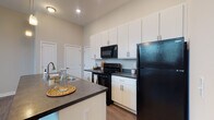 Located at 751 E Wheeling St in Lancaster, Ohio, this single-floor residence offers a thoughtfully designed layout with contemporary finishes throughout. The open-concept kitchen serves as the heart of the space, showcasing crisp white cabinetry extending to the ceiling, dark countertops, and a full suite of black appliances including a refrigerator, electric range, and over-the-range microwave. A central island with an integrated sink and pendant lighting overhead adds both functionality and visual appeal, making the kitchen ideal for cooking and casual dining. Wood-style plank flooring runs throughout the unit, lending warmth and continuity to the overall design. The bedrooms are generously sized with neutral-toned walls, ceiling fans, and ample natural light from window treatments. The bathrooms are finished consistently with the kitchen, featuring white vanity cabinetry, dark countertops, large mirrors, and wood-style flooring. One bathroom includes a shower-tub combination, while another is appointed with grab bars for added accessibility. Recessed and pendant lighting complement the airy feel of the space. The clean, neutral palette and modern fixtures create a cohesive and functional living environment throughout this well-appointed single-level residence.