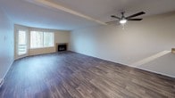 This single-floor unit offers a well-organized layout with a clear separation between living, cooking, and sleeping areas. The living room is generously sized, featuring dark wood-look vinyl plank flooring, a ceiling fan with integrated lighting, a baseboard heating unit, and a fireplace that serves as a natural focal point. Natural light filters in through a window, enhancing the open, airy feel of the space.

The kitchen is positioned adjacent to the living area and is equipped with white cabinetry, laminate countertops, white appliances including an electric range, and wood-look vinyl flooring that continues the cohesive aesthetic. Ample upper and lower cabinet storage makes the space highly functional.

Both bedrooms feature plush carpeting and baseboard heating. One bedroom includes a mirrored sliding closet door, adding a sense of depth, while both rooms receive natural light through blinds-fitted windows.

The unit includes two bathrooms. The first features a white vanity, wood-look flooring, and a combination tub and shower. The second is configured as a longer corridor-style bathroom with a single-sink vanity and a glass-enclosed walk-in shower. Both bathrooms maintain a clean, neutral aesthetic consistent with the rest of the unit.