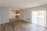 Located at 11844 Hamlin St, Unit 224 in North Hollywood, Los Angeles, this single-floor residence offers a clean, functional layout designed for comfortable everyday living. The main living area features durable wood-style plank flooring in a warm gray-brown tone, light blue-gray walls, and a textured ceiling that adds subtle character. A ceiling fan provides airflow throughout the open space, while a wall-mounted air conditioning unit ensures year-round climate control. A sliding glass door dressed with vertical blinds fills the room with natural light and provides an easy transition to the outdoors.

The galley-style kitchen is well-appointed with rich, warm-toned wood cabinetry extending from floor to ceiling on both sides, dark granite-style countertops, a double-basin sink, and black stainless steel appliances including a gas range and refrigerator. A window above the sink brings in additional natural light, keeping the space bright and airy.

The bathroom continues the cohesive design aesthetic with matching wood cabinetry, granite-style countertops, a large vanity mirror with globe lighting, and a shower/tub combination. The entry area features the same wood-style flooring and clean white walls, offering a welcoming and uncluttered arrival point into the unit.