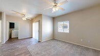 This single-floor, 2-bedroom, 2-bathroom residence features a practical and comfortable layout designed for everyday living. The open living and dining area is finished with wood-look flooring and ceiling fans, with a sliding glass door providing natural light and outdoor access. The kitchen stands out with dark navy cabinetry, white countertops, a peninsula island, and a full suite of stainless steel appliances including a refrigerator, range, and over-the-range microwave, all set on durable wood-look flooring. Both bedrooms are carpeted and fitted with ceiling fans and windows that allow natural light to filter in. The primary bedroom is generously sized and includes a walk-in closet with wire shelving for ample storage. The second bedroom also offers closet access and is equally well-lit. Each bathroom reflects a consistent design aesthetic — one features a dark-cabinetry vanity with a white countertop, a large mirror, and wood-look flooring, while the second includes a full soaking tub and shower combination. The dedicated laundry room houses a full-size washer and dryer and provides a window for ventilation. A connected hallway and entrance area complete this well-organized floor plan.