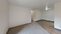 Located at 4317 NE 66th Ave in Vancouver, Washington, this single-floor, three-bedroom, two-bathroom home offers a practical and well-organized layout. The open-concept living and dining area features a combination of light hardwood-style flooring and plush carpeting, with clean white walls and a sliding glass door that leads to a private balcony overlooking greenery, filling the space with natural light. The kitchen is efficiently designed with dark cabinetry accented by bold purple upper cabinets, light hardwood-style floors, white appliances including a full-size refrigerator and range, and ample counter space. Each of the three bedrooms is carpeted and features large windows with blinds, baseboard heating, and generous closet space — with four closets distributed throughout the unit. The primary bedroom offers a comfortable footprint with its own dedicated closet. Both bathrooms are finished with light herringbone-pattern vinyl flooring and include a full tub and shower combination with clean white surrounds. Additional conveniences include a dedicated laundry room and a connecting hallway that ties the layout together. The home's neutral palette and functional design make it a versatile and move-in-ready space.
