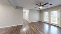 Located at 100 Parkridge Dr in Jackson, TN, this well-appointed 2-bedroom, 2-bathroom residence offers a comfortable and functional single-floor layout. The living room makes a strong first impression with rich hardwood-style flooring, a ceiling fan, and a set of French doors that fill the space with natural light and provide access to the outdoors. The galley-style kitchen is efficiently designed with white cabinetry, light countertops, a tiled backsplash, and a full suite of stainless steel appliances including a refrigerator, range, microwave, and dishwasher. A peninsula counter connects the kitchen to the adjacent living area, enhancing the open feel of the shared space. Both bedrooms feature plush wall-to-wall carpeting and ceiling fans, offering a cozy retreat. The primary bedroom includes a dedicated walk-in closet with built-in wire shelving and a sturdy storage bench. The two bathrooms are finished with wood-style vinyl flooring and include full tub-and-shower combinations. A hallway connects the private areas of the home, and neutral-toned walls throughout create a clean, move-in-ready aesthetic. Textured ceilings add a subtle design detail consistent across the entire residence.