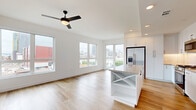 Located at 1509 Broadway in downtown San Diego, this thoughtfully designed 1-bedroom, 2-bathroom residence offers a clean, modern aesthetic across a well-organized single-floor layout. The open-concept living and kitchen area serves as the heart of the home, bathed in natural light from large windows that frame city views. Light-toned hardwood flooring flows throughout, complementing the bright white walls and creating a cohesive, airy ambiance. A sleek ceiling fan adds comfort to the spacious living area. The kitchen is outfitted with white shaker cabinetry, a subway tile backsplash, stainless steel appliances including a gas range, built-in microwave, and a French door refrigerator, all anchored by a center island with stone countertops and integrated shelving. The generously sized primary bedroom features a large window with urban views, a ceiling fan, and access to a walk-in closet with full shelving and hanging rails. The bathrooms maintain the home's modern palette with white vanities, black hardware accents, large-format tile flooring, and framed mirrors. Well-lit hallways connect each space efficiently. The overall design emphasizes clean lines, neutral tones, and functional living in the heart of San Diego.