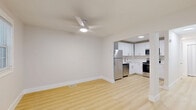 Located at 2000 24th Ave S in Nashville, TN, this single-floor unit offers three bedrooms, two bathrooms, a kitchen, a living room, and a closet — all thoughtfully arranged within a well-utilized floor plan. The kitchen is outfitted with white shaker cabinetry, light quartz countertops, stainless steel appliances including a range, built-in microwave, and dishwasher, all set atop light hardwood-style flooring that flows throughout the main living areas. The bathrooms feature striking marble-style wall panels with subtle grey veining, complemented by brushed gold hardware and a floating white vanity, lending a clean, upscale aesthetic. The bedrooms are finished with plush neutral carpet and ceiling fans, offering a comfortable and quiet retreat. Natural light enters through framed windows with blinds, brightening each room. The primary bedroom provides a generous layout with ample space. Additional bedrooms are versatile, suitable for sleeping quarters, a home office, or guest use. The overall design is clean and contemporary, with a consistent neutral palette of whites and warm beiges that gives the space a fresh, move-in-ready appeal throughout.