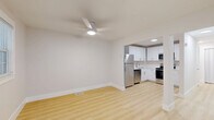 Located at 2000 24th Ave S in Nashville, TN, this single-floor unit offers three bedrooms, two bathrooms, a kitchen, a living room, and a closet — all thoughtfully arranged within a well-utilized floor plan. The kitchen is outfitted with white shaker cabinetry, light quartz countertops, stainless steel appliances including a range, built-in microwave, and dishwasher, all set atop light hardwood-style flooring that flows throughout the main living areas. The bathrooms feature striking marble-style wall panels with subtle grey veining, complemented by brushed gold hardware and a floating white vanity, lending a clean, upscale aesthetic. The bedrooms are finished with plush neutral carpet and ceiling fans, offering a comfortable and quiet retreat. Natural light enters through framed windows with blinds, brightening each room. The primary bedroom provides a generous layout with ample space. Additional bedrooms are versatile, suitable for sleeping quarters, a home office, or guest use. The overall design is clean and contemporary, with a consistent neutral palette of whites and warm beiges that gives the space a fresh, move-in-ready appeal throughout.
