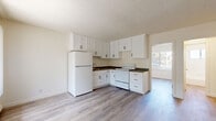 Located at 4070 Ursula Ave in Los Angeles, CA 90008, this one-bedroom, one-bathroom unit offers a thoughtfully organized single-floor layout. The open kitchen is a standout feature, outfitted with crisp white shaker-style cabinetry extending to the ceiling for generous storage, dark countertops, a white refrigerator, and a white electric range. Light wood-look flooring runs throughout the space, lending a clean and cohesive aesthetic. Natural light filters in through windows with vertical blinds, brightening the kitchen and living areas. The bedroom offers a comfortable footprint, complete with a ceiling fan with light fixture and a window framing views of surrounding greenery, including a palm tree — a nod to the Southern California setting. A hallway connects the main living areas to the bathroom, which features full white subway tile surrounding a shower-tub combo, a window for natural ventilation, and a clean, functional design. The textured ceiling is consistent throughout the unit. Overall, the space presents a bright, neutral palette that is move-in ready and well-suited for efficient, comfortable urban living in Los Angeles.