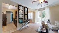 This single-floor residence offers a thoughtfully designed layout that balances comfort and functionality throughout. The living area is bright and welcoming, featuring plush carpeting, crown molding, ceiling fans, and a sliding glass door that opens to a covered porch with stacked-stone columns—an ideal spot for outdoor relaxation. A decorative console with geometric mirror panels serves as a stylish divider between the living space and the adjacent kitchen.

The kitchen is outfitted with stainless steel appliances, including a range, over-the-range microwave, and refrigerator, complemented by granite countertops and dark cabinetry. The dining area, finished with carpet and large windows, connects seamlessly to the living room, creating an open and airy flow.

The bedrooms are carpeted and naturally lit, each equipped with a ceiling fan and ample space. One bedroom doubles as a flexible study or sitting area. Both bathrooms feature granite-topped vanities, dark-framed mirrors, and tiled tub-shower combinations. A dedicated in-unit laundry closet with wire shelving adds everyday convenience. Throughout, warm neutral tones and consistent finishes create a cohesive, polished ambiance.