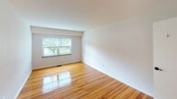 Located at 1825 Center St in Bethlehem, PA, this single-floor unit offers a clean, functional layout with notable design consistency throughout. Gleaming hardwood floors extend across the living, dining, and bedroom areas, lending warmth and a sense of continuity to the space. The open living and dining area is generously proportioned, featuring bright white walls, a chandelier accent, and multiple windows that invite natural light and views of the surrounding greenery. A separate bedroom provides a quiet retreat with its own window overlooking lush outdoor scenery and polished hardwood underfoot. The galley-style kitchen is efficiently designed with white cabinetry, dark granite-look countertops, tile flooring, and a full suite of stainless steel appliances including a gas range, over-the-range microwave, and refrigerator. A doorway from the kitchen connects seamlessly to the rest of the unit. The full bathroom is neatly appointed with a white vanity, mirrored medicine cabinet with built-in lighting, a toilet, and a tiled shower-tub combination. Clean white walls and classic tile work give the bathroom a timeless, well-maintained appearance. Overall, the unit presents a practical and inviting living environment in a residential Bethlehem neighborhood.