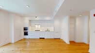 This thoughtfully designed 2-bedroom, 2-bathroom residence offers a clean, modern aesthetic throughout its single floor. Wide-plank hardwood floors in a warm natural tone run continuously across the living areas and bedrooms, creating a cohesive and inviting atmosphere.

The open-concept kitchen is a standout feature, showcasing floor-to-ceiling flat-front white cabinetry, a marble-style backsplash, and white quartz countertops. A stainless steel gas cooktop, double wall oven, and an undermount sink complete this well-appointed culinary space.

The living area flows seamlessly from the kitchen, benefiting from recessed lighting and crisp white walls. Both bedrooms are bright and functional, with one featuring large floor-to-ceiling windows that frame outdoor views and allow generous natural light to fill the room.

The two bathrooms reflect the same modern sensibility found throughout the home. One features a floating white vanity with a backlit mirror and a tub-shower combination with tile surround, while the second offers a sleek glass-enclosed walk-in shower with large-format tile, a window, and clean contemporary fixtures.

Additional highlights include two closets, a hallway with a centrally located electrical panel, and consistent recessed lighting throughout, all contributing to a polished and functional living environment.