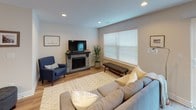 This two-floor home offers a well-organized layout with a thoughtful blend of functional design and comfortable finishes throughout. The main level centers around an open kitchen, which features warm honey-toned cabinetry, granite countertops, and stainless steel appliances including a gas range and built-in microwave. A generous island with pendant lighting provides additional prep space and flows naturally into the adjacent dining area, which benefits from recessed lighting and light hardwood flooring. The living area on this level includes a stone-surround fireplace with a dark wood mantle, adding a warm focal point to the space. Upstairs, the carpeted bedrooms provide a comfortable retreat. The primary bedroom is a spacious room with a ceiling fan, multiple windows allowing natural light, and access to a walk-in closet equipped with wire shelving and hanging rods. The ensuite bathroom features a dual-sink vanity with granite countertops, white cabinetry, and a glass-enclosed shower. Additional bedrooms share the same neutral palette and plush carpeting, each with windows and flush-mount lighting, offering versatile spaces suitable for various uses throughout the home.