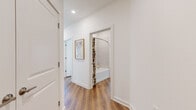 This thoughtfully designed single-floor residence offers 2 bedrooms and 2 bathrooms with a bright, modern aesthetic defined by crisp white walls, warm wood-look flooring, and recessed lighting throughout. The open-concept kitchen and living area serves as the heart of the home, featuring light wood cabinetry extending to the ceiling, a subway tile backsplash, granite countertops, stainless steel appliances, and a peninsula island with seating — ideal for both casual dining and entertaining. The adjacent living room receives generous natural light through large windows dressed with sheer curtains and blinds, creating an airy and welcoming atmosphere. The primary bedroom offers a comfortable sense of scale, a direct en-suite bathroom connection, and a walk-in closet with wire shelving systems for organized storage. The en-suite bathroom showcases a floating wood vanity with granite countertops and a large mirror with built-in lighting. A second well-sized bedroom and additional full bathroom with a tub/shower combination provide flexibility for guests or a home office. A dedicated laundry area and an impressive total of six closets round out the practical storage options. The clean, neutral design palette and consistent flooring tie the entire residence together cohesively.