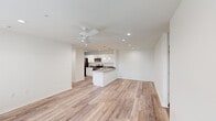 This single-story home in Biloxi, Mississippi offers a clean, modern aesthetic with five bedrooms, two full bathrooms, and a thoughtfully designed open-concept layout. The combined kitchen and living area serves as the heart of the home, featuring light wood-look luxury vinyl flooring, recessed lighting, and a ceiling fan that keeps the space airy and comfortable. The kitchen is outfitted with crisp white shaker-style cabinetry, granite countertops, stainless steel appliances including a range, microwave, and refrigerator, and a center peninsula that provides additional prep and seating space. Bright white walls and recessed lighting throughout the main living area create a fresh, welcoming ambiance. The hallways connect seamlessly to the bedrooms, some of which feature plush carpeting, ceiling fans, and windows with blinds that allow for natural light while maintaining privacy. Select bedrooms include wood-look flooring, offering versatility in use. Both bathrooms are finished with granite-topped white vanities, tub-shower combinations, and wood-look flooring, maintaining a consistent design language throughout. The home's neutral palette and modern finishes make it a move-in ready residence suited for comfortable everyday living in the Gulf Coast region.