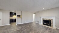 This well-appointed single-story, 2-bedroom, 2-bathroom home in Riverdale, GA offers a comfortable and functional layout throughout. The open living room serves as the heart of the home, showcasing rich hardwood-style flooring, a textured ceiling, recessed lighting, and a standout fireplace framed by a classic white mantel and mosaic tile surround. The adjacent kitchen is both stylish and practical, featuring dark espresso cabinetry, granite-look countertops, a tiled backsplash, stainless steel appliances including a gas range and dishwasher, and a pass-through bar connecting to the living area. Both bedrooms are carpeted for comfort, with neutral tones and natural light from windows fitted with blinds. The primary bedroom offers generous proportions and includes a closet with built-in shelving. The bathrooms are clean and functional, with a tub-shower combo and hardwood-style flooring. A dedicated laundry area with overhead cabinetry adds practical convenience. Neutral gray walls, consistent finishes, and a cohesive design palette give the home a move-in-ready feel throughout.