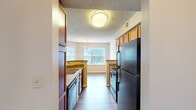 Located in Germantown, TN, this single-floor home offers three bedrooms, two bathrooms, and a thoughtfully designed layout. The galley-style kitchen is well-appointed with warm wood cabinetry, granite-look countertops, black appliances including a gas range and refrigerator, and durable hardwood-style flooring that extends into the adjoining dining area. A pendant chandelier adds a classic touch above the dining space, which benefits from natural light through a large window. The living room is a standout, featuring soaring vaulted ceilings, a ceiling fan with light kit, a tiled fireplace, and sliding glass doors that open to an outdoor area, inviting an abundance of natural light. The bedrooms are carpeted for comfort; the primary bedroom is generously sized and includes access to a spacious walk-in closet outfitted with wire shelving on multiple walls. Additional bedrooms feature carpet or hardwood-style flooring and multiple windows for natural light. The bathrooms are finished with rich wood vanities, granite-look countertops, large mirrors, and hardwood-style floors. Two hallways connect the space efficiently, completing this well-organized and comfortable home.