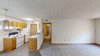 Located at 28 Sterling Ridge Dr in Delaware, Ohio, this well-organized 2-bedroom, 1-bathroom residence offers a practical single-floor layout designed for comfortable everyday living. The open living area features durable wood-look vinyl flooring and flows seamlessly into a half-wall peninsula kitchen equipped with warm honey-toned wood cabinetry, white appliances including an electric range and refrigerator, and ample counter space. A pendant chandelier illuminates the adjacent dining area, which connects to the main entry door. A hallway leads from the living space to the private areas of the home, where both bedrooms feature plush carpet flooring, neutral walls, and windows that provide natural light and views of surrounding greenery. The primary bedroom includes a spacious walk-in closet with wire shelving, while a second closet with sliding doors and built-in rod offers additional storage. The full bathroom is appointed with a single-sink vanity with wood cabinetry, a toilet, and a tub-shower combination. A textured ceiling is present throughout. The unit also includes a dedicated laundry area and benefits from a clean, neutral color palette throughout, making it a versatile and move-in ready space.