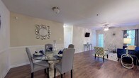 This single-floor residence in Riverdale, Georgia offers a thoughtfully designed layout with a cohesive aesthetic throughout. The open-concept living and dining area serves as the heart of the home, where rich wood-look flooring flows seamlessly between spaces. The living room features a ceiling fan with light fixture, a window allowing natural light, and ample space for comfortable seating arrangements. Adjacent to it, the dedicated dining area includes chair-rail molding along the walls, adding a classic architectural detail.

The kitchen is well-equipped with gray cabinetry, white countertops, a tile backsplash, and stainless steel appliances including a dishwasher and electric range. Wood-look flooring continues throughout this functional space, providing both style and easy maintenance.

The bedrooms feature plush carpeting and multiple windows that invite abundant natural light. The rooms offer generous proportions suitable for varied furniture arrangements.

Two full bathrooms are present, each featuring a tub-shower combination with tile surround, white vanities, and wood-look flooring. The neutral color palette maintained throughout the residence creates a clean, cohesive atmosphere that adapts easily to a variety of décor styles.