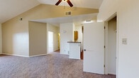 This efficiently designed one-bedroom, one-bathroom unit offers a comfortable and functional layout across a single floor. The open-concept living room and kitchen area is anchored by vaulted ceilings and a ceiling fan, creating a sense of generous vertical space. Soft carpet flooring extends throughout the living area and bedroom, while the kitchen features durable wood-look flooring. A sliding glass door leads to a private balcony overlooking a landscaped outdoor area, flooding the living space with natural light.

The galley-style kitchen is well-appointed with warm honey-toned wood cabinetry, granite-look countertops, a double-basin sink, and black appliances including a refrigerator and electric range. A breakfast bar peninsula connects the kitchen to the main living area, offering additional counter space and a casual dining option.

The bedroom is a comfortable size, featuring two windows with vertical blinds, a ceiling fan with light fixture, and direct access to a dedicated closet with built-in shelving. The bathroom includes a full-size tiled tub-shower combination, providing practical functionality. Overall, the unit presents a clean, neutral palette throughout, making it a versatile and move-in ready space.