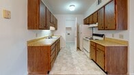 Located at 838 S Parker Dr in Florence, South Carolina, this single-floor unit offers a functional and straightforward layout designed for comfortable everyday living. The living area is generously sized, featuring warm neutral carpet, a textured ceiling, and a sliding glass door that brings in natural light and provides access to an outdoor balcony. A chandelier-lit dining area connects seamlessly to the galley-style kitchen, which is outfitted with rich oak cabinetry, laminate countertops, a double sink, a white electric range, refrigerator, and light tile flooring — providing ample storage and prep space. The bedrooms are carpeted and well-proportioned, each featuring windows with vertical blinds that allow for natural light and privacy. The full bathroom includes a tub and shower combination with chrome fixtures and stone-look tile flooring, while a separate half bath offers added convenience. A dedicated laundry area with washer and dryer hookups, overhead shelving, and tile flooring adds practical utility to the unit. Throughout the space, neutral tones and clean white trim create a bright, cohesive aesthetic well-suited for a variety of furnishing styles.