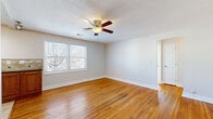Located at 3936 Pennsylvania Ave in Kansas City, MO, this single-floor, 2-bedroom, 1-bathroom home offers a practical and cohesive layout. Warm-toned hardwood floors run throughout the living areas and bedrooms, lending a consistent and inviting character to the space. Ceiling fans are present in every room, contributing to both comfort and airflow.

The living room is bright and open, with natural light streaming through large windows. It flows into the kitchen, which is well-appointed with warm oak cabinetry, a tile backsplash, dark countertops, and stainless steel appliances including a range, microwave, and dishwasher. Light tile flooring grounds the kitchen area.

The primary bedroom offers a comfortable footprint, featuring a ceiling fan, natural light from a window, and access to a closet. The second bedroom also includes a ceiling fan and dual windows that fill the room with natural light. Both bedrooms feature the same warm hardwood flooring found throughout the home. Built-in closets with rods provide practical storage.

The bathroom includes a full bathtub with a showerhead, speckled surround walls, and a frosted privacy window. A hallway connects the rooms efficiently, completing this compact yet well-organized home.