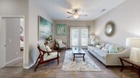 Located in Gulf Shores, Alabama, this well-appointed 2-bedroom, 2-bathroom residence offers a thoughtfully designed single-level layout. Wood-look flooring flows throughout the main living areas, lending a clean, cohesive aesthetic. The living room is bright and welcoming, featuring a ceiling fan, a coastal-inspired décor palette, and French doors that open to bring in natural light and outdoor views. Adjacent to the living room, the dining area accommodates a full table setting beneath a pendant light fixture. The kitchen is equipped with white shaker-style cabinetry, granite-look countertops, black appliances, a tile backsplash, and a peninsula with a sink — providing ample prep and storage space. A dedicated laundry room with a full-size washer and dryer adds everyday convenience. The primary bedroom is generously sized with plush carpeting, a ceiling fan, and a walk-in closet outfitted with wire shelving. The second bedroom also features carpet and a ceiling fan. Both bathrooms are finished with wood-look tile flooring, white vanities with granite-look countertops, and shower/tub combinations. The neutral color palette and coastal accents throughout create a calm, comfortable ambiance well-suited to the Gulf Shores setting.