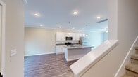 Located at 1817 Ferndale Ct in Chattanooga, TN, this two-story home presents a clean, modern aesthetic throughout its thoughtfully designed layout. The main level centers around an open-concept living and kitchen area finished with durable wood-look flooring and crown molding. The kitchen is well-appointed with white shaker cabinetry, granite countertops, a subway tile backsplash, stainless steel appliances, and a central island with a built-in sink and pendant lighting overhead. Recessed lighting and a ceiling fan complement the bright, airy atmosphere of the living area, which also connects to a separate room featuring French doors that open to an outdoor patio, allowing natural light to fill the space. A dedicated laundry room with wire shelving and washer/dryer hookups adds everyday convenience on this level. Upstairs, the bedrooms are carpeted for comfort and include ceiling fans, ample closet space with built-in shelving, and windows that invite natural light. A full bathroom on the upper level features a granite-topped vanity with white cabinetry and a tub-shower combination. The home's neutral color palette and consistent finishes create a cohesive, move-in-ready environment throughout.