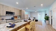 Located in Chandler, AZ, this two-story home offers 2 bedrooms, 3 bathrooms, and a flexible office space across two well-proportioned floors. The main level provides the bulk of the living space and features an open-concept kitchen and living area. The kitchen is appointed with light wood cabinetry, granite countertops, stainless steel appliances, and a large island with bar seating — all set atop light-toned hardwood-style flooring with recessed lighting above. The living room is bright and airy, with sliding glass doors that open directly to a private outdoor patio area with turf, extending the living space outdoors. The bathrooms mirror the home's modern aesthetic, featuring wood-tone vanities with granite counters, tub-shower combinations with built-in shelving, and windows that bring in natural light. Upstairs, the spacious primary bedroom features vaulted ceilings, plush carpeting, and access to a walk-in closet. The secondary bedroom and additional office space are also carpeted, each equipped with ceiling fans and ample natural light through large windows. With two dedicated closets and three full bathrooms, this home is designed for comfort and practicality in equal measure.
