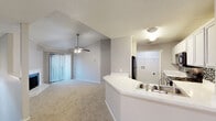 Located at 4447 Rainier St in Irving, TX, this two-bedroom, two-bathroom two-story home offers a well-organized and functional layout. The main level hosts the primary living spaces, including a combined living room, dining room, and kitchen that flow seamlessly together. The living room is a standout, featuring a white-brick fireplace, plush carpet flooring, a ceiling fan, and sliding glass doors with vertical blinds that open to a private balcony, filling the space with natural light. The kitchen is equipped with white cabinetry, a mosaic tile backsplash, white countertops, black appliances, and a peninsula with a built-in sink that serves as a natural divider between the kitchen and living areas. Carpeted stairs with a white railing and a window-lit stairwell lead to the upper level. Both bedrooms are carpeted and feature dedicated closets, with the primary bedroom offering generous proportions. The bathrooms include wood-look flooring and white vanities. Additional highlights include a dedicated laundry area and five closets throughout, providing exceptional storage. Textured ceilings are found throughout, and the neutral gray walls create a clean, versatile backdrop throughout the entire home.