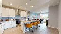 This thoughtfully designed 2-bedroom, 2-bathroom residence spans a single floor and features a contemporary open-concept layout with light wood-style flooring throughout. The gourmet kitchen is outfitted with crisp white cabinetry, a light gray subway tile backsplash, stainless steel appliances including a gas range and built-in microwave, and a center island with quartz countertops and stylish bar seating. The kitchen flows seamlessly into the dining area, which features a window with outdoor views, and into the bright living room, where large sliding glass doors open to a private balcony and fill the space with natural light. A ceiling fan adds comfort to the living area. The primary bedroom is a serene retreat highlighted by a bold blue accent wall, large windows with neighborhood views, and access to a spacious walk-in closet with full wire shelving systems. The second bedroom features a rich rust-red accent wall and ample natural light. Both bathrooms are finished with neutral tile, and one includes a full soaking tub and shower combination. Additional highlights include a dedicated dining room, a full in-unit laundry room with a side-by-side washer and dryer, and a welcoming entrance, making this a complete and functional living space.